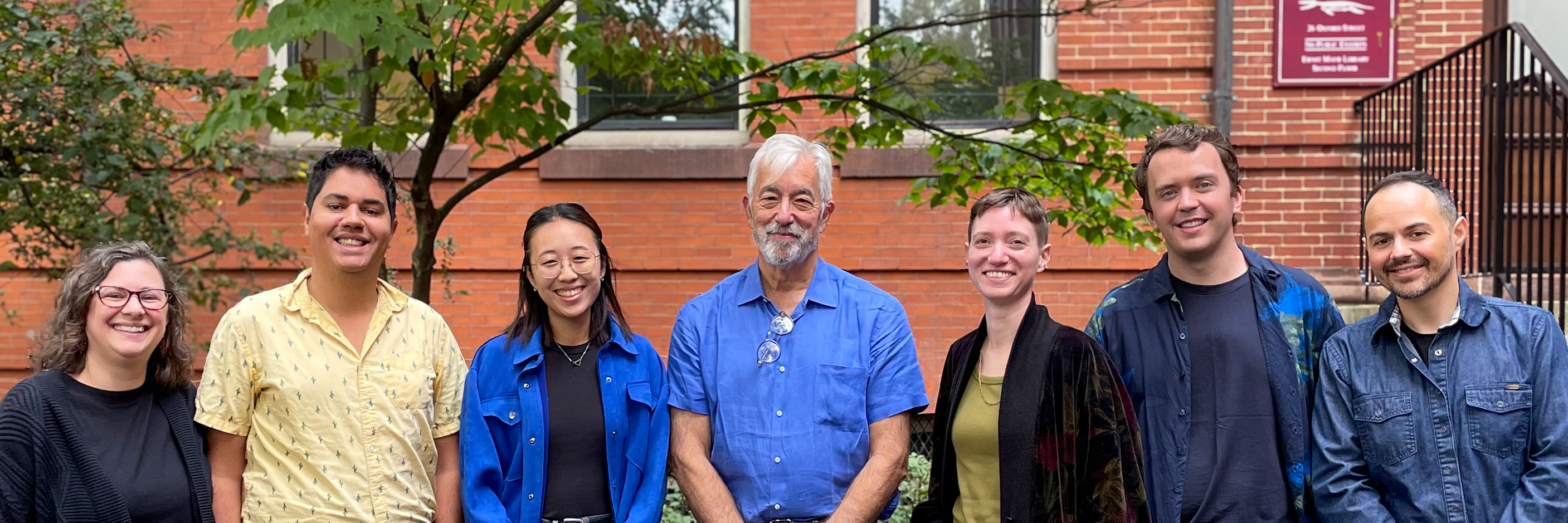 2024 Farrell Lab group photo, 7 people in front of leaves & brick
