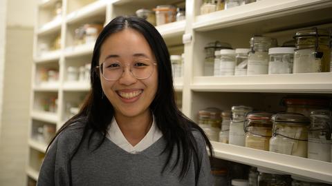 Kaylin Chong in front of shelves of museum specimens in jars