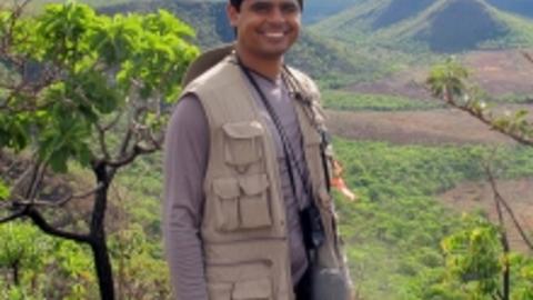 Bruno, standing with green mountains and trees behind him
