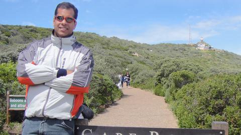 Fabio Laurindo da Silva outdoors, leaning against sign for Cape Point, South Africa