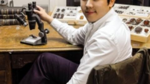 Sang Il Kim at desk with microscope