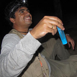 Bruno wearing headlamp, holding container of beetles at night