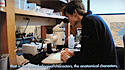 Screenshot of video, showing Jessica Rykken looking into microscope in lab