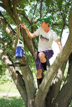 Paige climbs a tree to move collecting gear