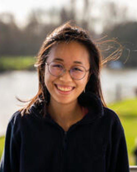 portrait of Kaylin Chong, wearing glasses outdoors on breezy day, blurred background