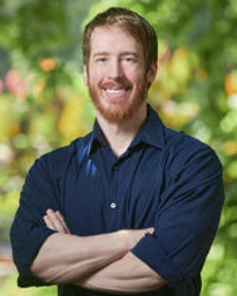 Headshot of Patrick Gorring, blurry leaves in background