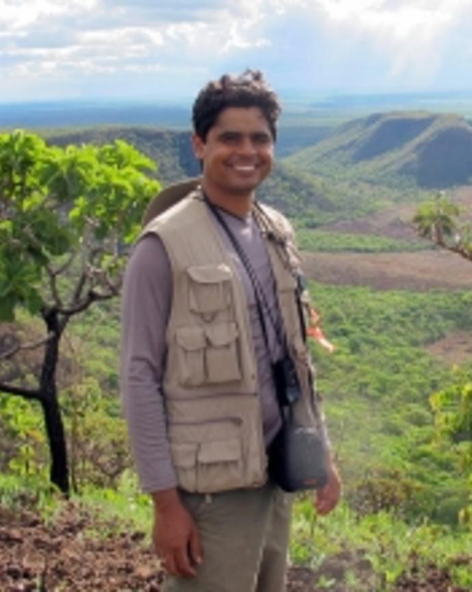 Bruno, standing with green mountains and trees behind him